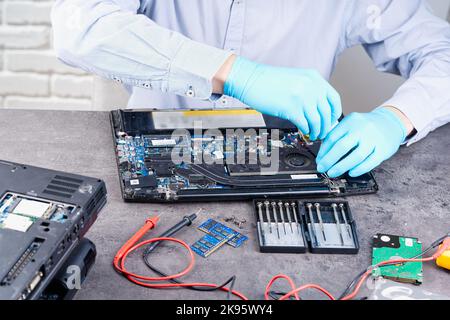 Hands of a technician repairing a broken laptop computer Stock Photo