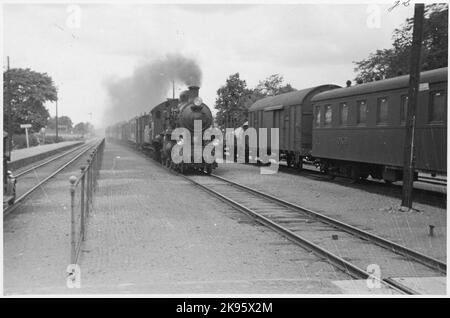 Knivsta station. Snap train drawn by the State Railways, SJ B 1385 rolls into the station. To the right Cars East Coast Line, OKB C01 82. Signpost Stockholm C. Stock Photo