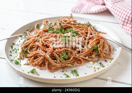 Whole wheat spaghetti with homemade tomato sauce and parmesan cheese on a plate isolated on white wooden background Stock Photo
