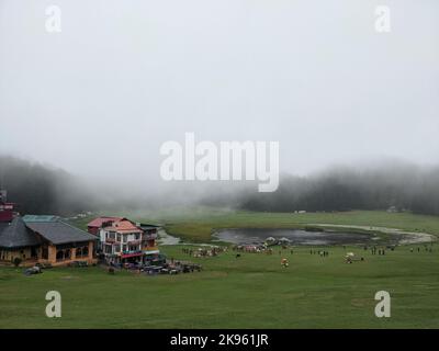 A beautiful shot of people gathering in Khajjiar Town with dense fog covering the forest in the background, Himachal Pradesh, India Stock Photo