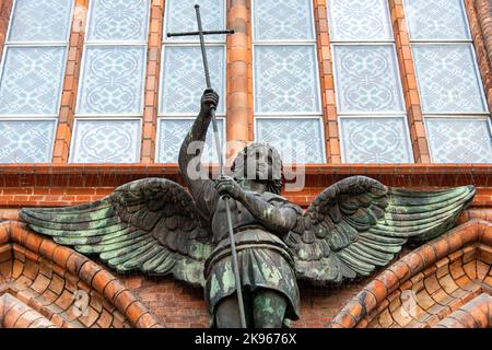 Statue of Archangel Michael killing the snake, Christian church exterior details. Catholic temple in Berlin, Germany, gothic architecture. Stock Photo