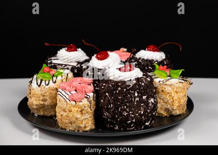 Cakes with chocolate, cherries and cream on a black background. Stock Photo