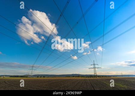 Electricity pylon for transmission and current transfer of high voltage through natural landscapes in front of a cloudy sky Stock Photo
