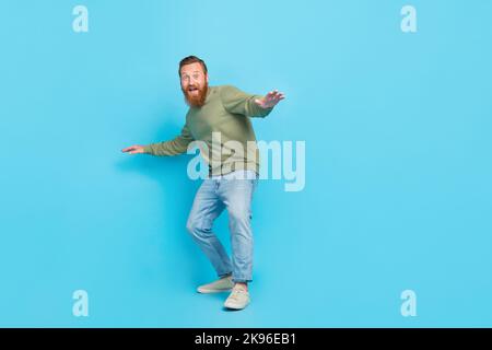 Full length photo of cheerful impressed guy ginger hairdo khaki long sleeve hold balance catch wave isolated on blue color background Stock Photo