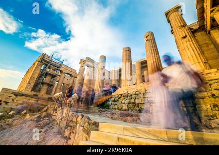 Crowd of tourists walking around in front of the ancient ruins of Parthenon building at sunset Stock Photo