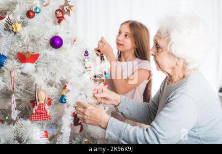 Granddaughter with grandma decorating christmas tree Stock Photo