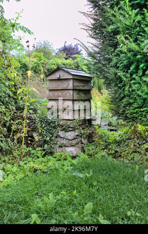 Traditional feather edge board bee hive on stone plinth in Gilbert Whites Hampshire garden Stock Photo