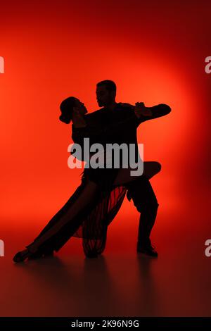 Silhouette of couple dancing tango on red background Stock Photo
