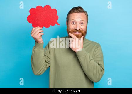 Photo portrait of nice young guy touch beard hold comics dialog thought paper cloud wear khaki garment isolated on cyan color background Stock Photo