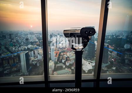 Binoculars or telescope on top of skyscraper at observation. A device for sightseeing from the top of a skyscraper. Saigon or Ho Chi Minh city. Vietna Stock Photo