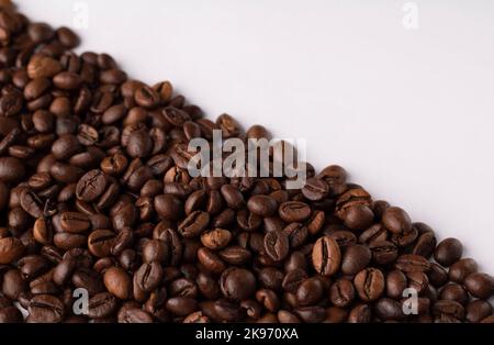 photo whole coffee beans lying on the side of the table on a white background Stock Photo