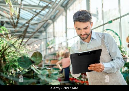 male florist taking notes on the clipboard. Stock Photo