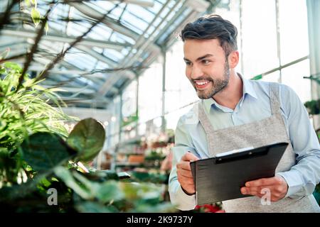 male florist taking notes on the clipboard. Stock Photo