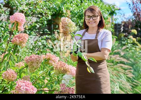 Portrait of gardener woman with pruner looking at camera in garden Stock Photo