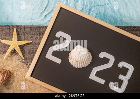Happy New Year 2023 concept with a shell and a starfish by a pool. Winter vacations in the sun. Stock Photo
