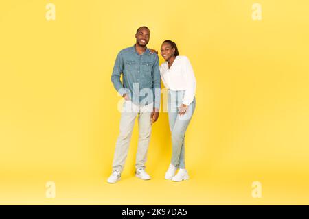 Full Length Of African American Couple Posing Over Yellow Background Stock Photo