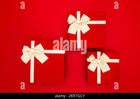 Red gift boxes tied with golden ribbons on a red background Stock Photo