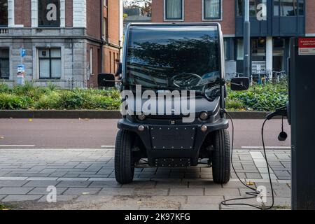 Amsterdam, The Netherlands, 26.10.2022, Modern two-seat electric micro car being charged in the street Stock Photo