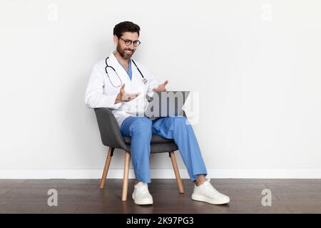 Telemedicine Concept. Smiling Male Doctor Using Laptop For Teleconference With Patient Stock Photo