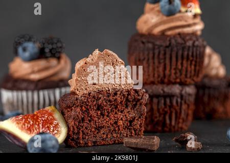 Chocolate cupcakes. Blueberry fig. Half a cream muffin. Muffins with cream and fruit on a dark background Stock Photo