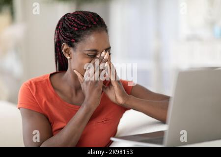 Eyes Fatigue. Young Black Woman Feeling Tired After Using Laptop At Home Stock Photo