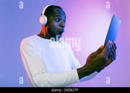 Amazed african american man using headphones and digital tablet Stock Photo