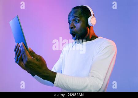 Emotional black man with wireless headset using digital tablet Stock Photo