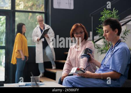 Nurse doing cardiology exam with instrument to measure hypertension and ...