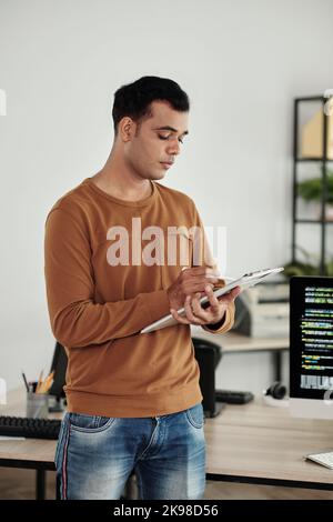 Portrait of software engineer writing his ideas in document on clipboard Stock Photo