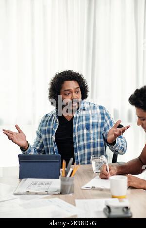 Emotional team leader talking to middle software developer at meeting Stock Photo