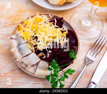 Sliced herring with grated beetroot and cheese served on table Stock Photo