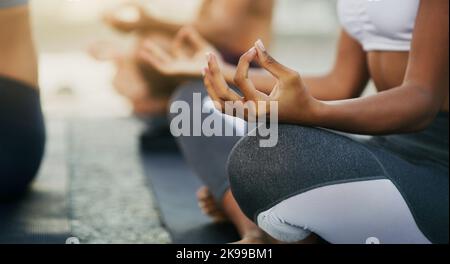 We are whole in ourselves. an unrecognizable group of people sitting and meditating together while on the beach during an overcast day. Stock Photo
