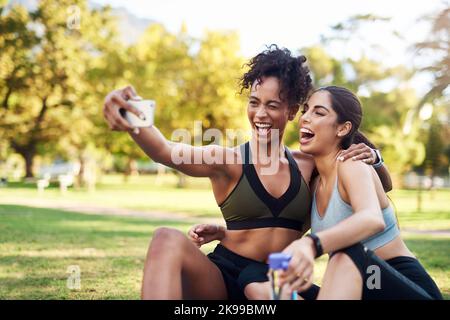 Staying positive after a good workout. two attractive young women posing for a selfie while in the park during the day. Stock Photo