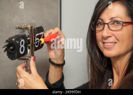 Watchmaker is repairing the analog table mechanical clock in her workshop. Stock Photo