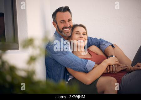 Isnt Cupid just a master of his art. an affectionate mature man embracing his wife while sitting outdoors. Stock Photo