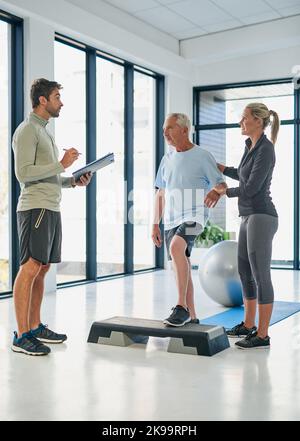 Hes not alone on this journey. Full length shot of two friendly physiotherapists working with a senior patient. Stock Photo