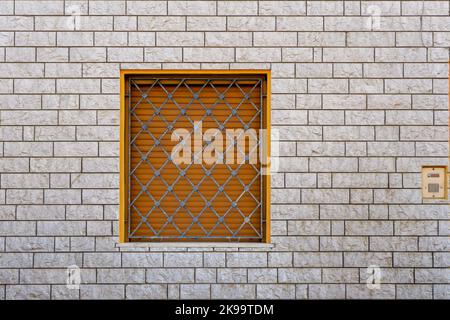 A modern facade covered with white stone brick and windows protected with metal bars Stock Photo