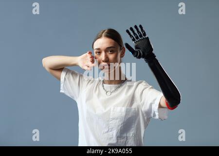Portrait of girl with disability with prosthetic arm standing against on blue background Stock Photo