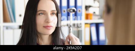 Neurologist doctor driving hammer tool in front of patient eyes in clinic, checkup Stock Photo