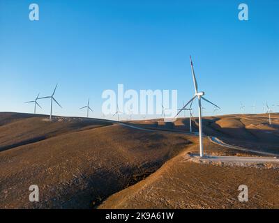 Aerial view of multiple wind turbines standing on a hill and generating ...