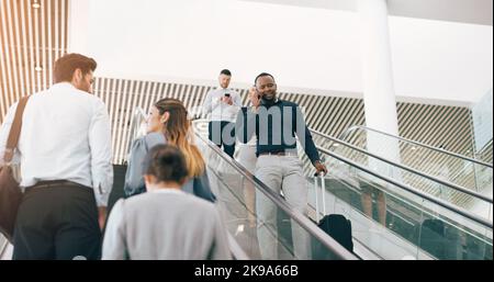 Everyones heading to where they need to be. a handsome young businessman taking a phonecall while going down an escalator in a modern workplace. Stock Photo