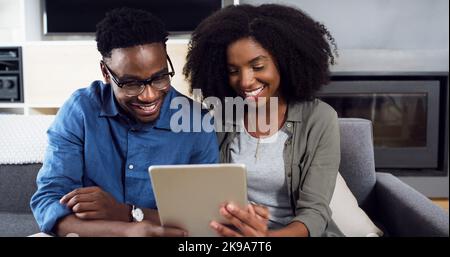 We definitely have to try that out. a cheerful young couple using a digital tablet together at home. Stock Photo