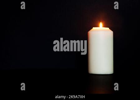 white burning candle on black background. burns in darkness, copy space. eternal memory, mourning, Stock Photo