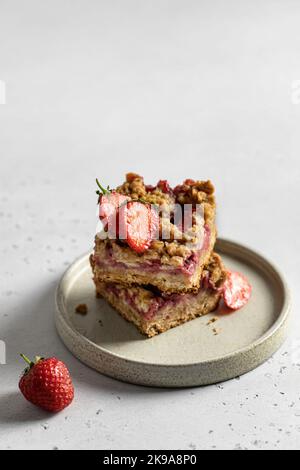 Two pieces of oatmeal crumble strawberry bars on the plate on light background isolated with text space Stock Photo