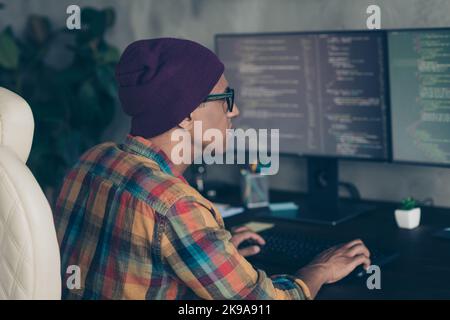 Photo of serious clever programmer wear spectacles hat writing code modern gadget indoors workplace workshop home Stock Photo