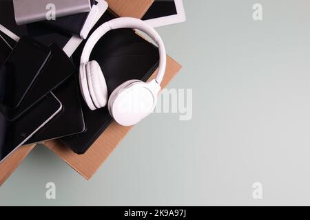 Cardboard box full of old used laptop computers, digital tablets, smartphones, power bank for recycling on gray background. Donation, e-waste Stock Photo