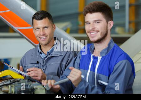 happy two mechanics working in a hangar Stock Photo