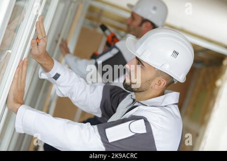 construction worker putting sealing foam tape on window in house Stock Photo