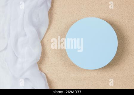 Empty round blue platform podium and white crumpled linen fabric cloth on onatural beach sand background. Minimal creative composition background for Stock Photo