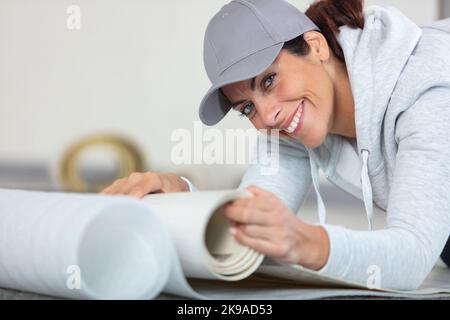 smiling female worker with a roll of linoleum Stock Photo